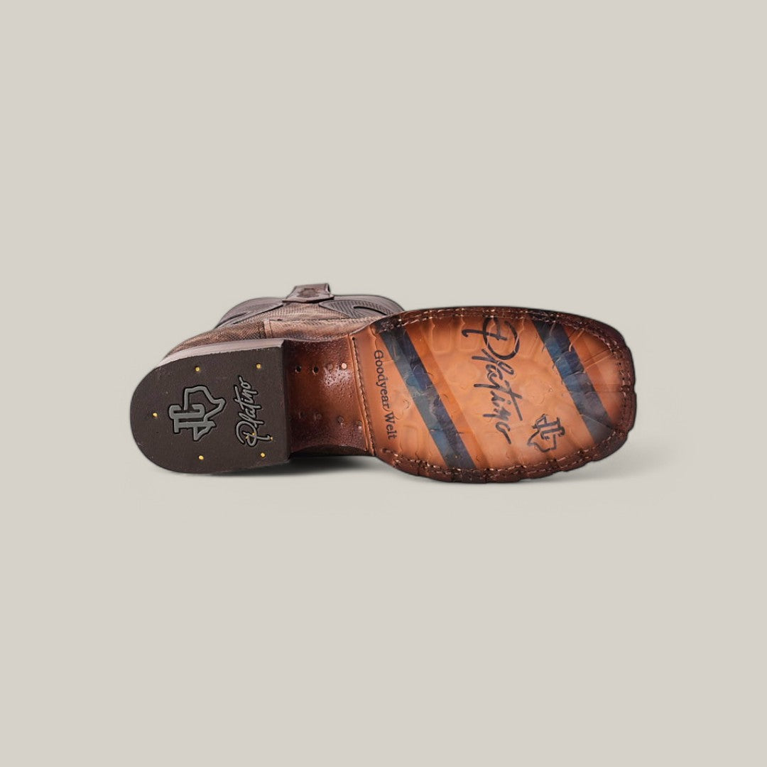 The image highlights the sole of the Exotic Carunga - Diamond - Natural - Double Sole Square Toe cowboy boot, featuring Western craftsmanship, decorative stitching, a logo, and colored stripes. Set against a neutral backdrop, it emphasizes the boots exceptional design elements.