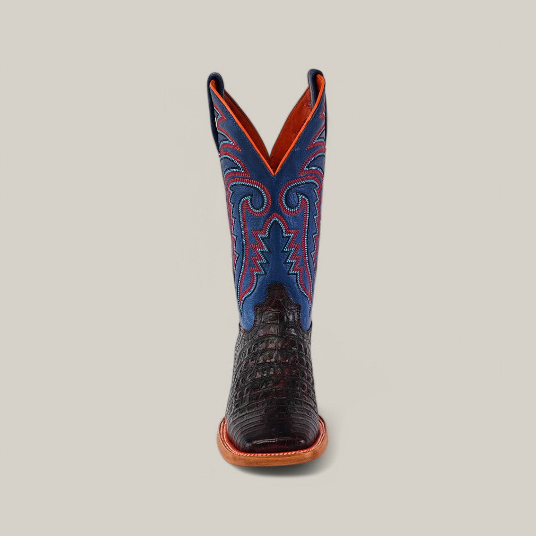 The Exotic Caiman Belly - Black Cherry - Square Toe boot features a handcrafted design with a black crocodile-textured lower half and blue upper section, adorned with red and blue stitching. Reminiscent of its counterpart, it stands upright against a plain background to highlight its exotic leather finish.