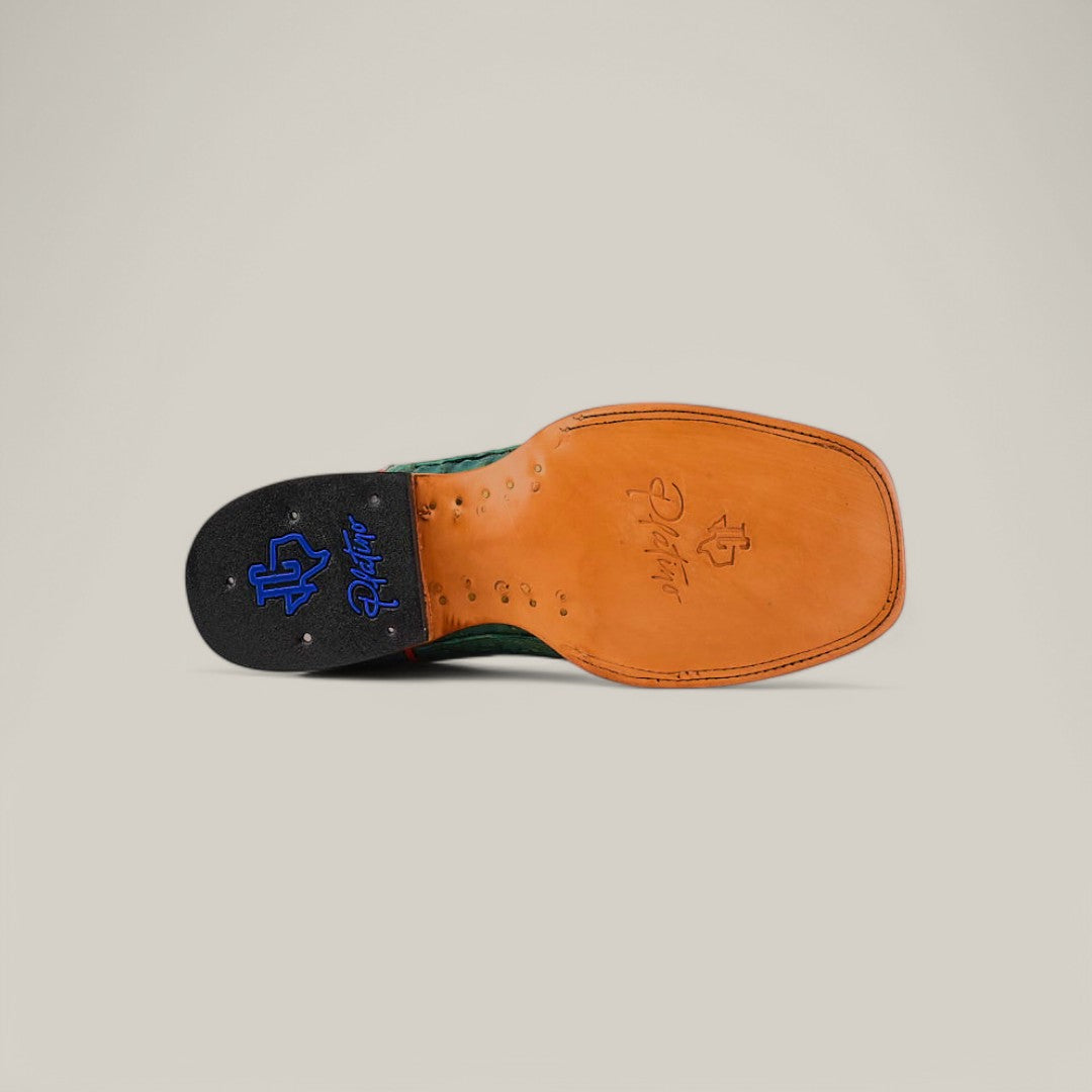 The image shows the sole of an Exotic Caiman Belly Tail - Green - Square Toe shoe with a tan leather finish made from premium caiman leather, featuring blue and black logos—one with initials, another script-style signature. Its set against a plain light beige background, emphasizing its exotic pattern.