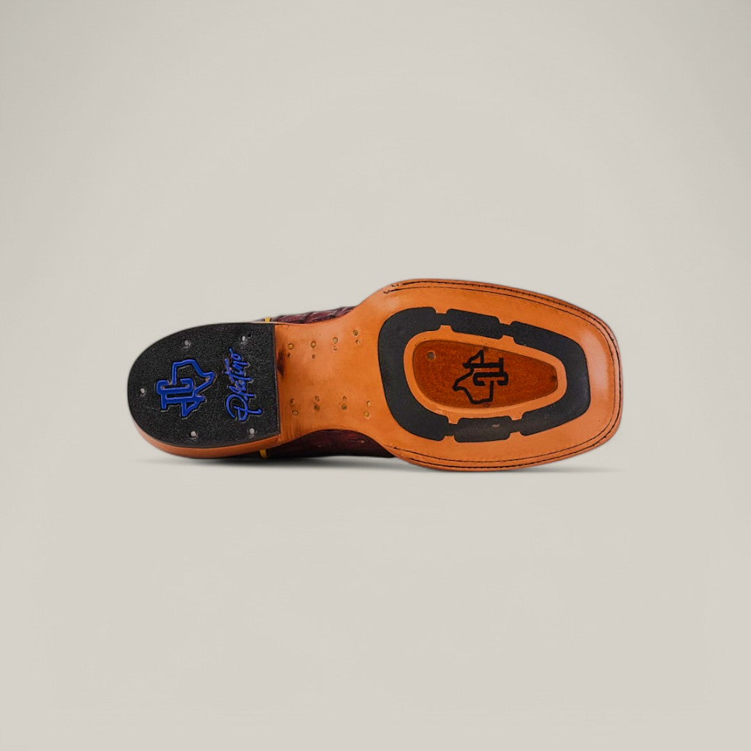 The image showcases the Exotic Caiman Belly Tail Wine boot with a square toe, blending leather and rubber, featuring a black and blue logo. The unique design rests on a plain beige background.