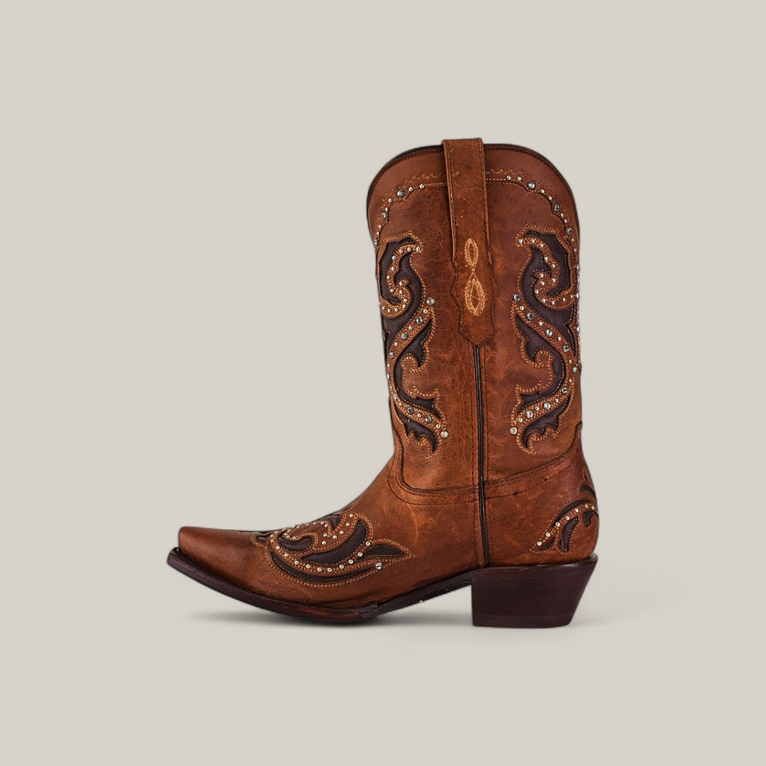 The Dolly - Brown - Snip Toe boot from the Last Call collection features brown leather with black and tan embroidery, decorative studs, a pointed toe, low heel, and pull strap. Shown in profile on a plain light background.