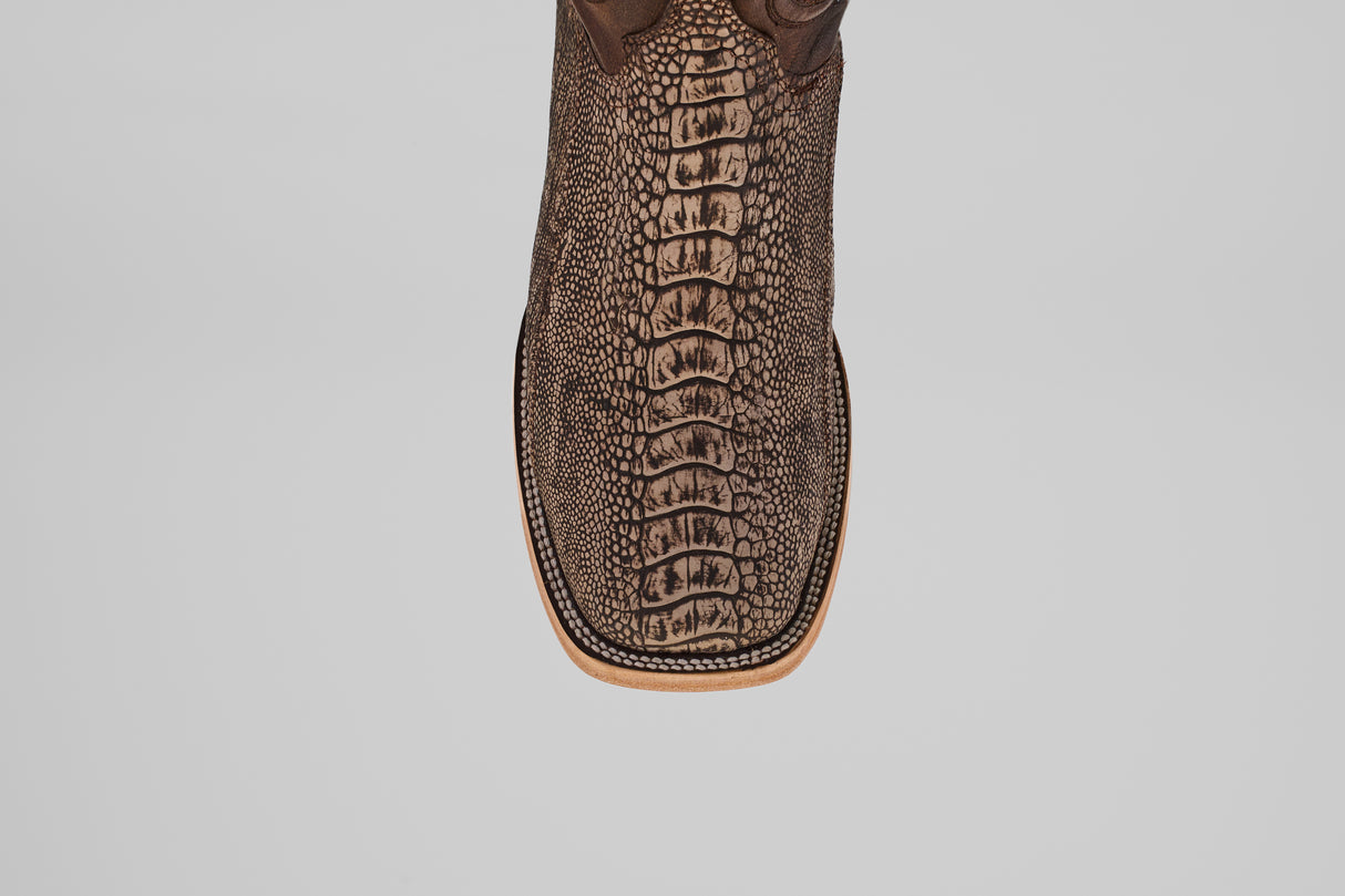 A close-up, top-down view of the Exotic Full Quilt Ostrich Leg - Matte Orix square toe boot features detailed stitching and a textured brown upper, resembling an exotic pattern, set against a plain white background.