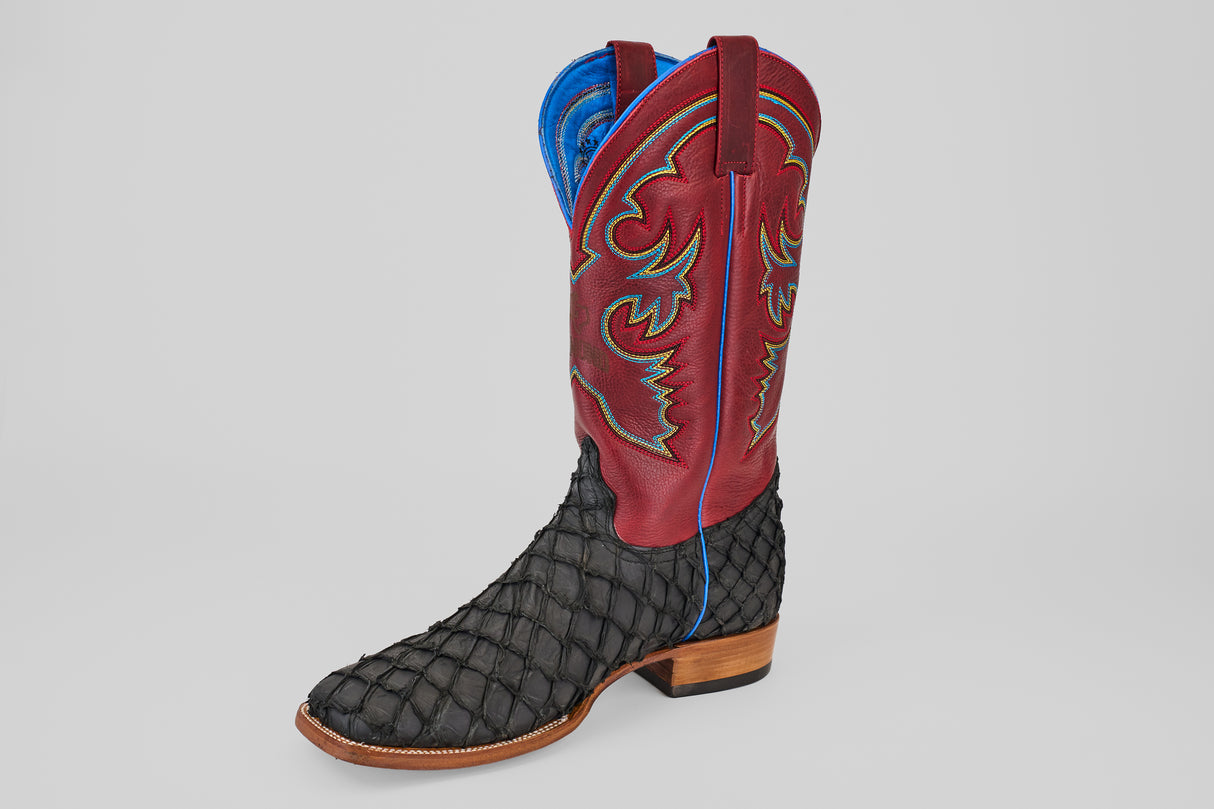 The Dodge - Matte Black - Square Toe men’s luxury boot features a textured black Pirarucu leather lower, tall red stitched upper, blue lining, and a wooden heel, all displayed against a plain light background.