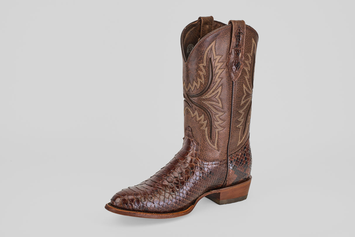 A single Tanner - Brown - Round Toe cowboy boot features textured, snakeskin-like leather and intricate upper stitching, displayed against a light gray background—perfect for stylish outings at the Python Cafe Oval.