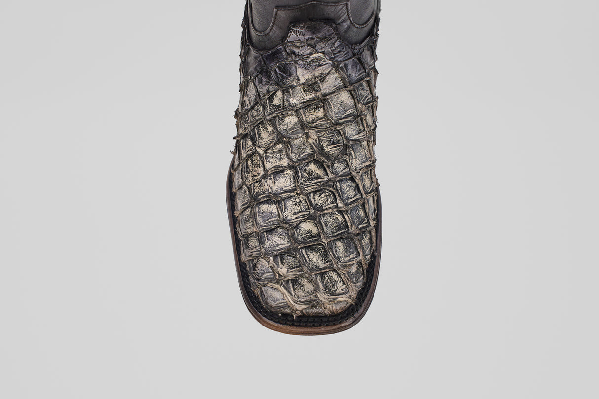 A close-up of the Conor Platinum - Newspaper - Square Toe (Diamond) cowboy boot, featuring dark, textured crocodile-patterned leather and a brown edge, displayed against a plain white background.