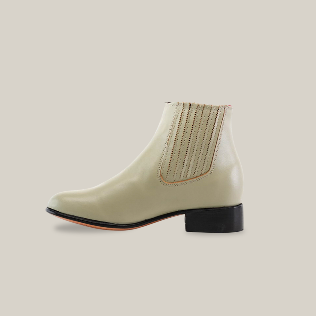 As part of the Western Wear Collection, the Napa Bone - Round Toe ankle boot in light beige boasts a low black heel. Its sleek design features visible stitching on the elastic side panel and a smooth texture, beautifully contrasted against a plain white background.