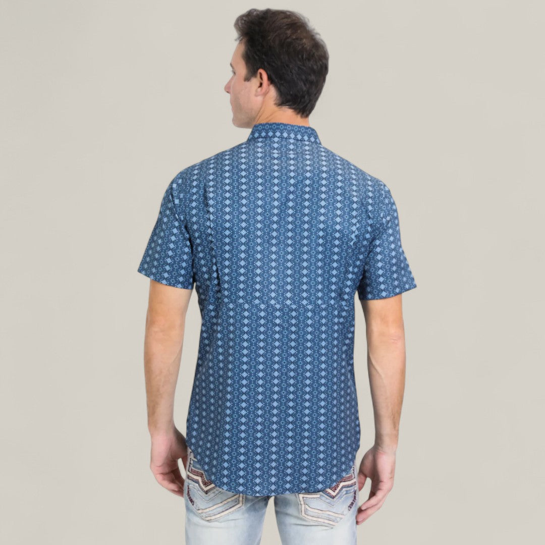 A man faces away from the camera in a Mens Performance Western Short Sleeve Aztec Print Navy Shirt (PGS10659) and light blue jeans with decorative back pocket stitching, standing against a plain background.