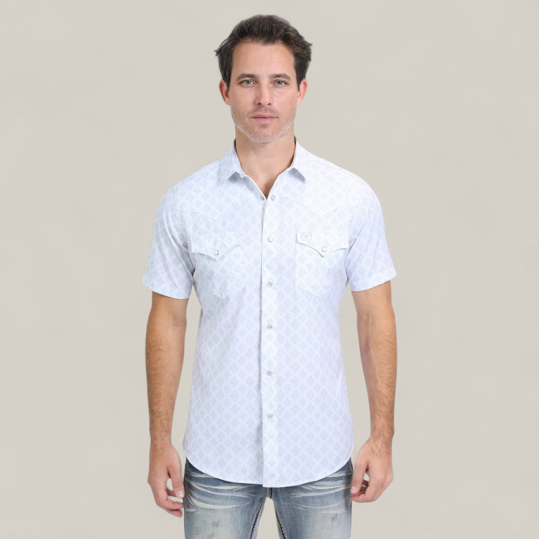 A man with short dark hair wears the Mens Performance Western Short Sleeve Aztec Print White Shirt (PGW10631) with faded jeans, standing against a plain light beige background and looking directly at the camera.