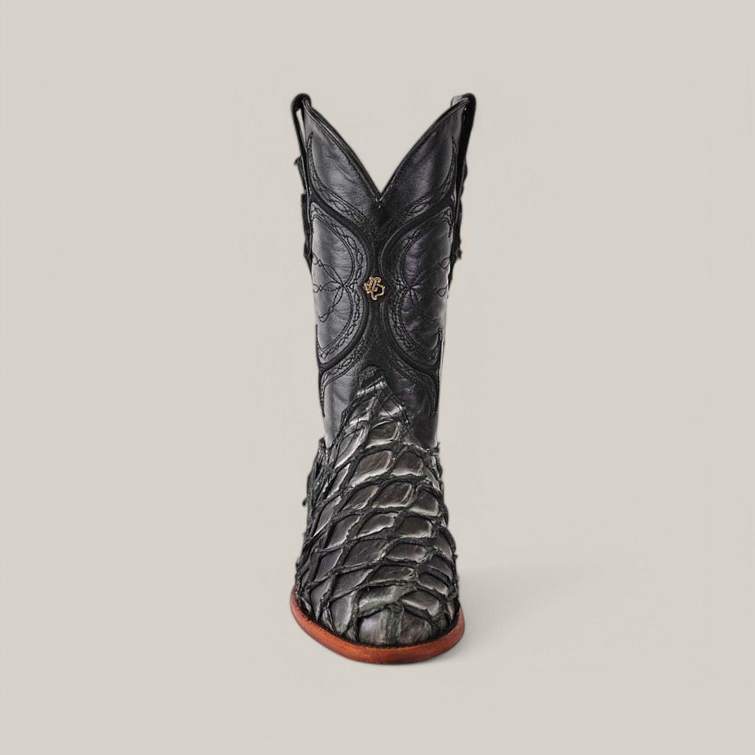 The Exotic Pirarucu Fish - Newspaper - Roper Toe is a luxurious black cowboy boot made from textured Pirarucu leather, showcasing intricate stitching and a front emblem, elegantly standing against a plain gray background.