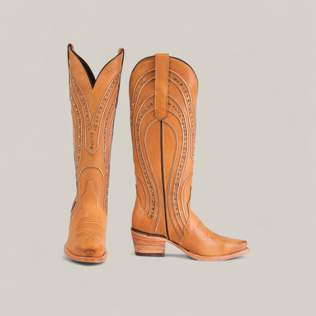 A pair of tall, tan leather cowboy boots with decorative stitching and studs, standing on a plain light background; one boot faces forward, the other to the side.