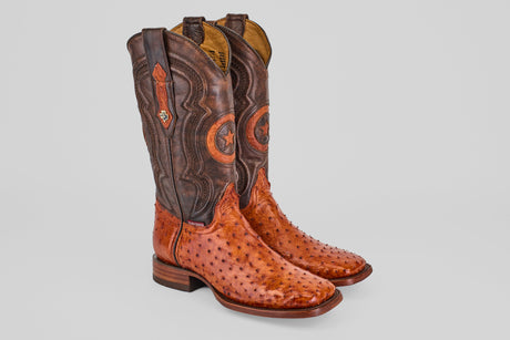 A pair of dark red ostrich leather cowboy boots with decorative stitching, one boot standing upright and the other lying on its side, both with light brown soles.