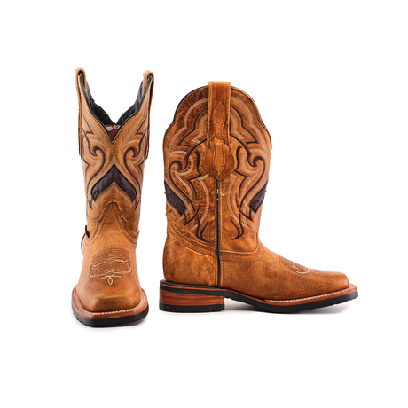 The Wild Mustard Slip Resistant Sole Rodeo Toe boots are a pair of brown cowboy boots made from cowhide leather, featuring intricate black and tan stitching on the shaft and a rodeo toe. One boot stands upright while the other is tilted to highlight their elegance, leather finish, stacked heel, and slip-resistant sole.