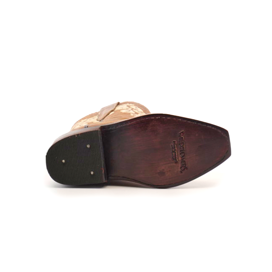 The image features the sole of a Martey Crystals Sahara - Snip Toe cowboy boot in light brown, with intricate stitching and rubber grips. A dark brown heel complements the logo on the sole, set against a white background.