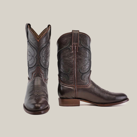 A pair of Rush Brown - Roper Toe cowboy boots features intricate stitching on premium cowhide leather. Displayed on a white background, the left boot faces forward, and the right shows a side profile.