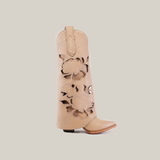 The Roma Flowers Tall Shaft Cream - J Toe boot stands upright against a white background, showcasing intricate floral cutouts on its beige shaft. It features a slightly pointed toe, sturdy leather soles, and a low heel.