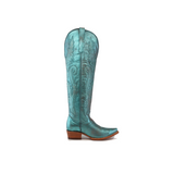 A single turquoise Brittany Rustic Ceramic Tall Shaft Snip Toe Boot displays intricate stitching, patterns, a pointed toe, and a wooden heel. This handcrafted boot features a genuine leather sole on a pristine white background.