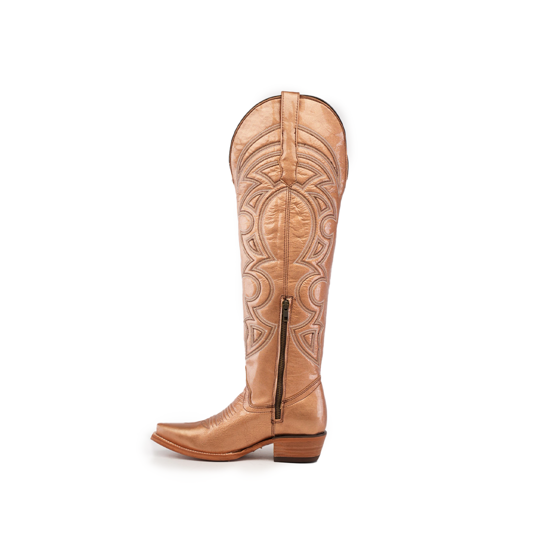 The Taylor Rose Gold knee-high boot, in tan leather, showcases detailed stitching, a side zipper, and a snip toe for an authentic Western style. Its tall shaft and low wooden heel merge classic design with modern flair.