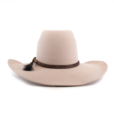 The 6X Brazil Belly is a beige wide-brimmed hat made from genuine sheep wool, featuring a tall crown and enhanced with a premium leather band with woven details and a small black feather.