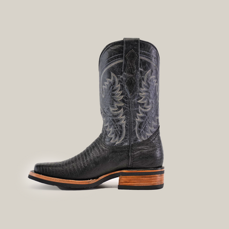 The Lizard Print Black cowboy boot, made from premium cowhide leather with intricate embroidery, features a rodeo toe and a wooden heel. It includes a slip-resistant sole and is elegantly displayed against a plain white background.