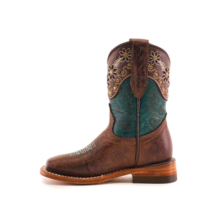 The Grecas Tabaco - Square Toe is a premium leather brown cowboy boot, featuring intricate floral embroidery and turquoise detailing on the shaft. Its smooth texture, low heel, and sole stitching blend rustic charm with colorful elements through traditional craftsmanship.