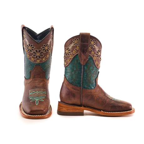 The Grecas Tabaco - Square Toe boots feature intricate turquoise embroidery and floral patterns. One boot displays its toe and shaft design, while the other emphasizes detailed stitching and a sturdy heel. Both handcrafted brown boots stand upright against a white background, showcasing traditional craftsmanship.