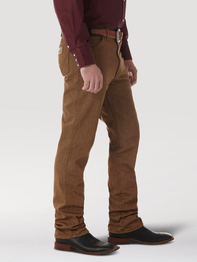 A person dressed in a maroon long-sleeve shirt, Wrangler Cowboy Cut Slim Fit Jean - 100936BKW, and black leather shoes with brown soles stands against a plain white background, wearing a brown belt with a silver buckle. The persons hands rest naturally by their sides.