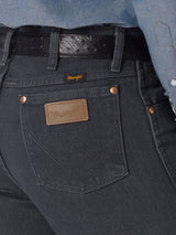 Close-up of a person in Wrangler Cowboy Cut Slim Fit Jean, 0936CHG, with visible pocket stitching and a brown leather label. Paired with a black belt and light blue shirt.