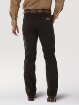 A person seen from the back is wearing a brown long-sleeve shirt and Wrangler Cowboy Cut Slim Fit Jeans (0936KCL) in dark brown with pockets and button details, accessorized with a leather belt. They stand against a light, neutral background.