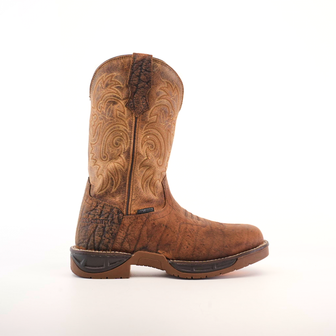 A Tan Brown Rough out boot, made from premium cowhide leather with decorative stitching and a rugged sole, is showcased on a white background. Its worn texture emphasizes its rustic style and the handcrafted excellence that makes it unique.