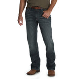 A person is wearing a dark green T-shirt tucked into faded premium denim, secured with a brown leather belt, and paired with brown cowboy boots. The outfit features Mens Wrangler 20X No. 42 Vintage Bootcut Jean - 42MWXGG. Only the lower body is visible.