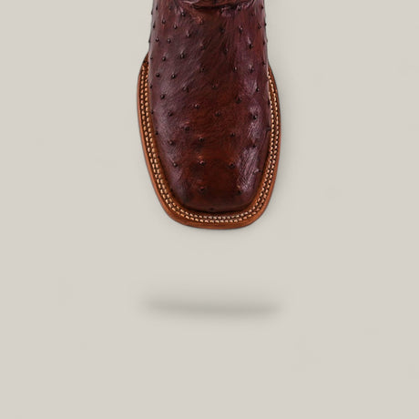 Close-up of the Exotic Full Quilt Ostrich - Red / Brown - Square Toe boot, highlighted from above to showcase decorative stitching, part of the Platinum Collection, displayed on a light beige background with a subtle shadow.