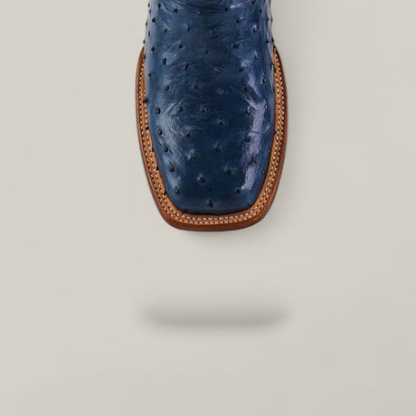 Top view of the Exotic Full Quilt Ostrich - Blue - Square Toe boot, highlighting its stylish square toe and tan welt stitching on a light gray background. The blue ostrich boot casts a soft shadow below.