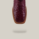 A close-up of the Exotic Full Quilt Ostrich - Wine - Square Toe boot highlights its rich wine-colored ostrich leather, sophisticated square toe, and brown stitched welt, set against a plain light gray background with a subtle shadow.