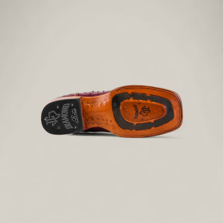 A close-up of the Exotic Full Quilt Ostrich - Wine - Square Toe shoe sole, featuring rich wine ostrich leather, signature branding, a textured rubber heel for grip, and a sophisticated square toe—shown against a neutral background.