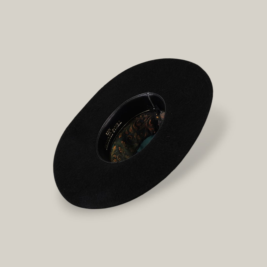 The 25X Grizzly - Black - TC Hat is a wide-brimmed luxury black hat with a decorative patterned inner band, shown from above on a plain beige background.
