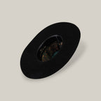 The 25X Grizzly - Black - TC Hat is a wide-brimmed luxury black hat with a decorative patterned inner band, shown from above on a plain beige background.