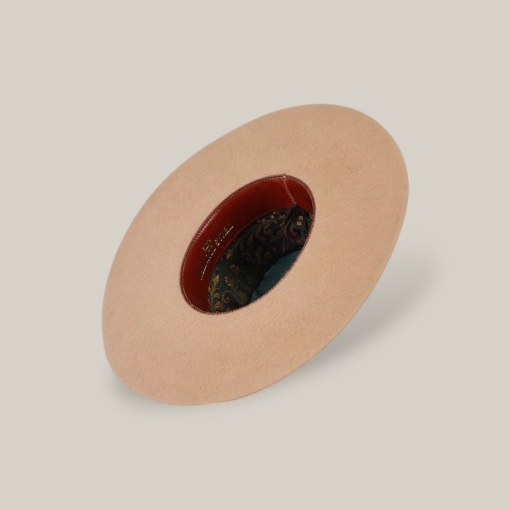 The 25X Grizzly - Belly - TC Hats is displayed upside down, featuring a tan wide brim, brown leather inner band, and multicolored paisley-patterned lining against a plain light background.