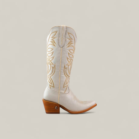 The Kellie Frost White Leather Sole boot features a tall shaft, snip toe, light tan decorative stitching, and a wooden angled heel set against a light beige background.