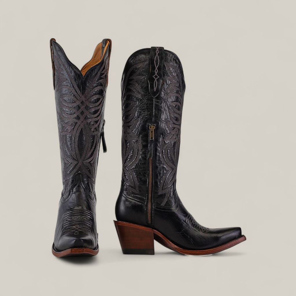 The Kellie Clayton Black Leather Sole boots feature a tall shaft, snip toe, and high wooden heels with intricate stitching and side zippers, displayed against a plain beige background.