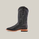 The Exotic Full Quilt Ostrich Black cowboy boot, with a square toe and textured ostrich leather, features a low wooden heel and pull strap. Set against a plain beige background, its side profile is highlighted.