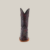 The Exotic Full Quilt Ostrich in Black Cherry is a single cowboy boot made from genuine ostrich leather with intricate textures and small raised bumps. It features a square toe and brown sole, set against a plain beige background.