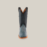 Front view of the Exotic Full Quilt Ostrich in Blue Jean with a textured blue leather foot and a smooth dark shaft featuring decorative stitching, all set against a plain beige background. The boot includes pull straps and has a brown sole.