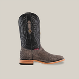 The Exotic Python - Matte Gray - Square Toe cowboy boot showcases a black upper and textured gray-brown python leather lower. It features intricate stitching, a leather sole, and a small red label by the heel, all set against a plain beige background.