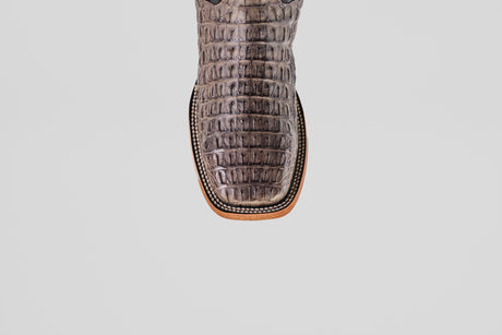 A close-up of the Exotic Caiman Horn Back - Serpentine - Square Toe boot’s brown, crocodile-embossed leather toe with detailed edge stitching, shown against a plain white background.
