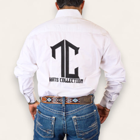 A man is seen from behind wearing the TC Hats - White & Black button-down shirt with a large TC logo on the back, paired with blue jeans and a patterned belt, against a plain background.