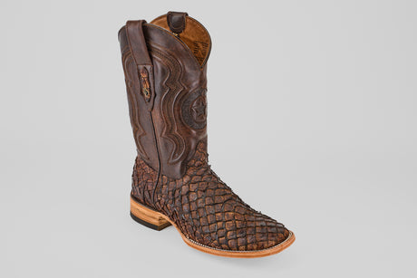 The Exotic Pirarucu Fish - Brown - Square Toe boot features textured, scale-like leather on the foot, decorative shaft stitching, and a light wooden sole, shown solo against a plain gray background.