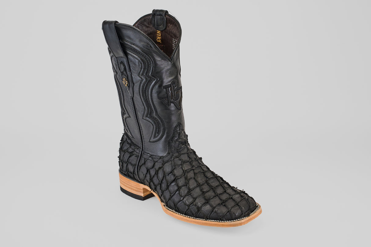 The Exotic Pirarucu Fish - Matte Black - Square Toe boot features textured, scaly exotic leather, detailed shaft stitching, and a light wooden heel and sole, shown against a plain light gray background.