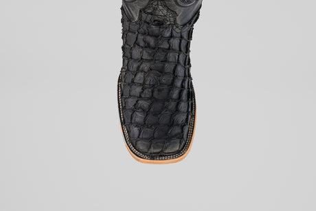 A close-up of the Exotic Pirarucu Fish boot in matte black, featuring a textured finish, square toe, and light brown sole, set against a plain light gray background.