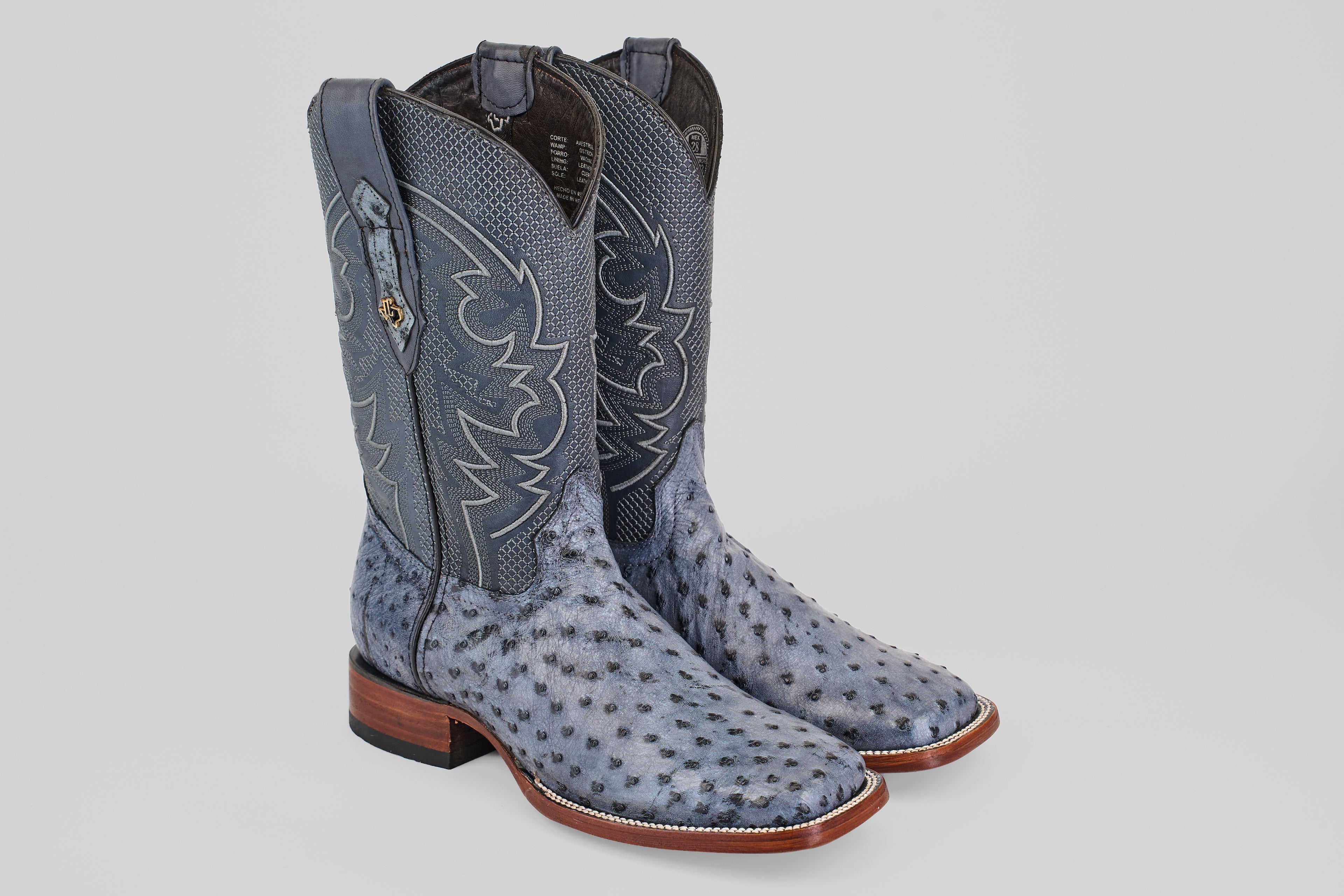 Exotic Full Quilt Ostrich boots in Safari Gray feature decorative stitching, square toes, and brown wooden heels, displayed on a light background.