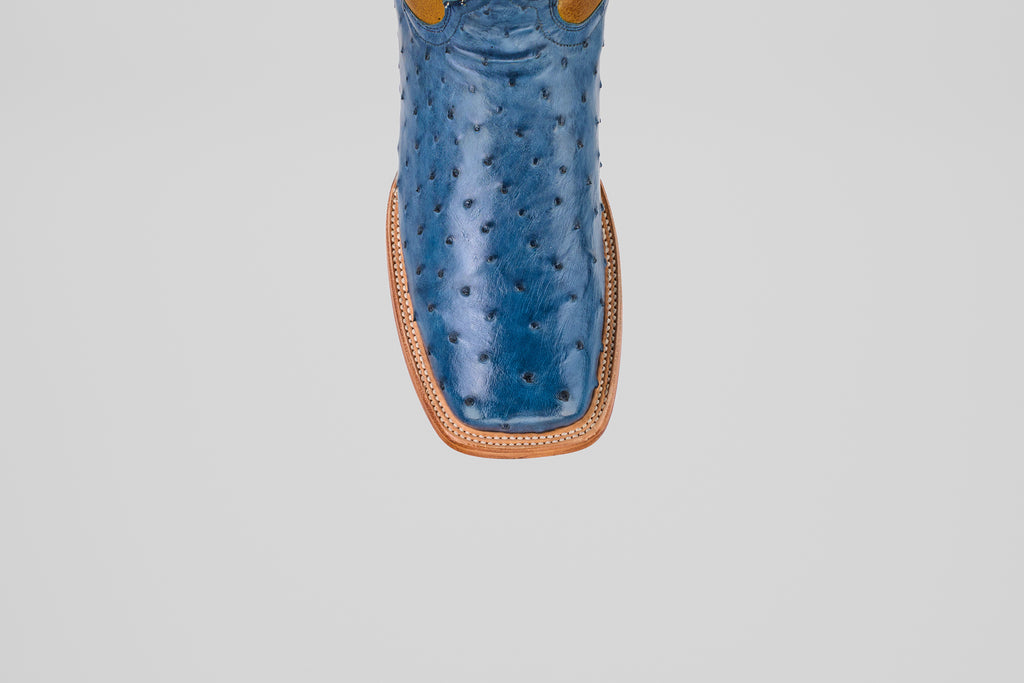 A top view close-up of the Ridge - Blue - Square Toe boot, crafted from blue ostrich leather with a tan welt and square toe, shown on a plain light gray background.